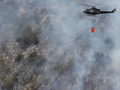 A Montenegrin army helicopter helps to extinguish a forest fire, during a heatwave, over the touristic area of Boka Bay in the city of Perast, Montenegro, August 10, 2022. REUTERS/Stevo Vasiljevic MONTENEGRO OUT. NO COMMERCIAL OR EDITORIAL SALES IN MONTENEGRO