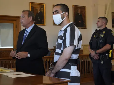 Hadi Matar, 24, center, listens to his public defense attorney Nathaniel Barone, left, addresses the judge while being arraigned in the Chautauqua County Courthouse in Mayville, NY., Saturday, Aug. 13, 2022. Matar, accused of carrying out a stabbing attack against "Satanic Verses" author Salman Rushdie, has entered a not-guilty plea on charges of attempted murder and assault. (AP Photo/Gene J. Puskar)