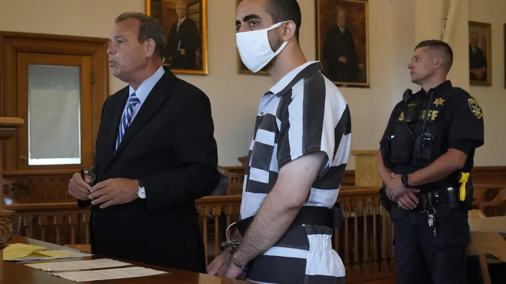 Hadi Matar, 24, center, listens to his public defense attorney Nathaniel Barone, left, addresses the judge while being arraigned in the Chautauqua County Courthouse in Mayville, NY., Saturday, Aug. 13, 2022. Matar, accused of carrying out a stabbing attack against "Satanic Verses" author Salman Rushdie, has entered a not-guilty plea on charges of attempted murder and assault. (AP Photo/Gene J. Puskar)
