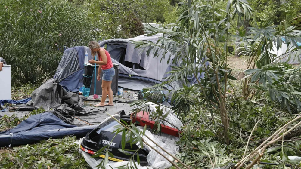 18 August 2022, France, Coggia: A woman packs up the remains of destroyed tents and other items at the Sagone campsite, where a tree fell on a bungalow during a storm, killing one person. Several people have died in violent storms on the French Mediterranean island of Corsica. Photo: Pascal Pochard-Casabianca/AFP/dpa