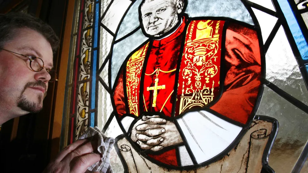 Parish priest Guenter Christoph Haase cleans the new church window showing a portrait of former Pope John Paul II, by Polish artist Monika Klas, at St. Nicholas Cathedral in Heuthen, eastern Germany, Wednesday, Dec. 7, 2005. It is one of the first church windows in Germany with a Pope John Paul II portrait. (AP Photo/Jens Meyer)