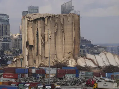 A collapsed portion, right, lies on the ground of the silos that damaged during the August 2020 massive explosion in the port, in Beirut, Lebanon, Tuesday, Aug. 23, 2022. The ruins of the Beirut Port silos' northern block that withstood a devastating port explosion two years ago has collapsed. The smoldering structure fell over on Tuesday morning into a cloud of dust, leaving the southern block standing next to a pile of charred ruins. (AP Photo/Hussein Malla)