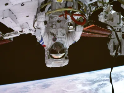 In this photo released by Xinhua News Agency, screen image captured at the Beijing Aerospace Control Center on Sept. 1, 2022 shows Shenzhou-14 astronaut Chen Dong exiting the space station lab module Wentian orbiting earth. The Shenzhou 14 Chinese space crew started a series of extravehicular activities on Thursday evening, according to space media reports. (Li Jie/Xinhua via AP)