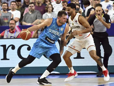 Germany's Nick Weiler-Babb and Slovenia's Luka Doncic, left, fight for the ball during the Eurobasket preliminary round Group B match between Germany and Slovenia in Cologne, Germany, Tuesday, Sept. 6, 2022. (Federico Gambarini/dpa via AP)