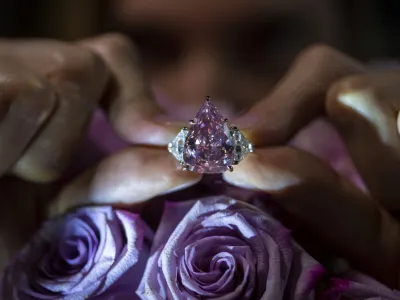 A Christie's employee displays a pink diamond called "The Fortune Pink" of 18,18 carat, during a preview at Christie's, in Geneva, Switzerland, Wednesday, Nov. 2, 2022. The pear-shaped 18-carat pink diamond is set to be sold at auction on Tuesday and is expected to fetch between  million and  million. (Martial Trezzini/Keystone via AP)
