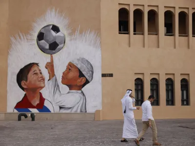 Soccer Football - FIFA World Cup Qatar 2022 Preview - Doha, Qatar - November 9, 2022 People walk past a football mural on the walls of Katara Cultural Village ahead of the World Cup REUTERS/John Sibley