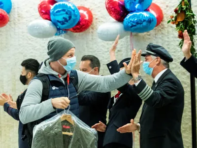 ﻿A man gives a high five to the crew members as he exits baggage claim after landing in the British Airways flight at JFK International Airport in New York, U.S., November 8, 2021. REUTERS/Eduardo Munoz