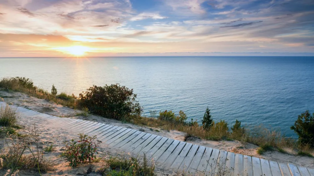 ﻿A colorful sunset over Lake Michigan shines its light on this boardwalk on Empire Bluff Trail near Empire Michigan. This trail overlooks Sleeping Bear Dunes