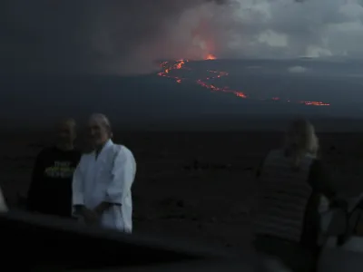 Spectators take photos as they watch the lava flow down the mountain from the Mauna Loa eruption, Tuesday, Nov. 29, 2022, near Hilo, Hawaii. (AP Photo/Marco Garcia)