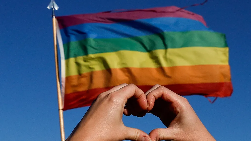 A person holds their hands in the shape of a heart in front of a pride flag during a march for solidarity for the those affected after a mass shooting at LGBTQ nightclub Club Q, in Colorado Springs, Colorado, U.S. November 26, 2022. REUTERS/Isaiah J. Downing   TPX IMAGES OF THE DAY