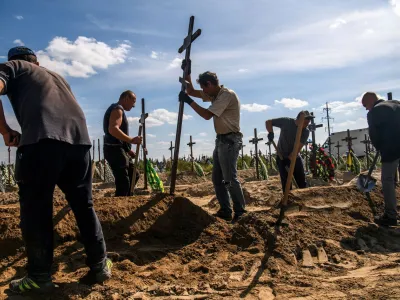 FILE PHOTO: A volunteer places a cross onto a grave of one of fifteen unidentified people killed by Russian troops, amid Russia's attack on Ukraine continues, during a burial ceremony in the town of Bucha, in Kyiv region, Ukraine September 2, 2022. REUTERS/Vladyslav Musiienko/File Photo