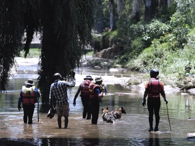 Rescue workers search the waters of the Jukskei river in Johannesburg, Sunday, Dec. 4, 2022. At least nine people have died while eight others are still missing in South Africa after they were swept away by a flash flood along the Jukskei river in Johannesburg, rescue officials said Sunday. (AP Photo)