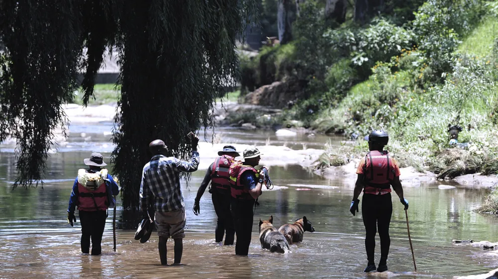 Rescue workers search the waters of the Jukskei river in Johannesburg, Sunday, Dec. 4, 2022. At least nine people have died while eight others are still missing in South Africa after they were swept away by a flash flood along the Jukskei river in Johannesburg, rescue officials said Sunday. (AP Photo)