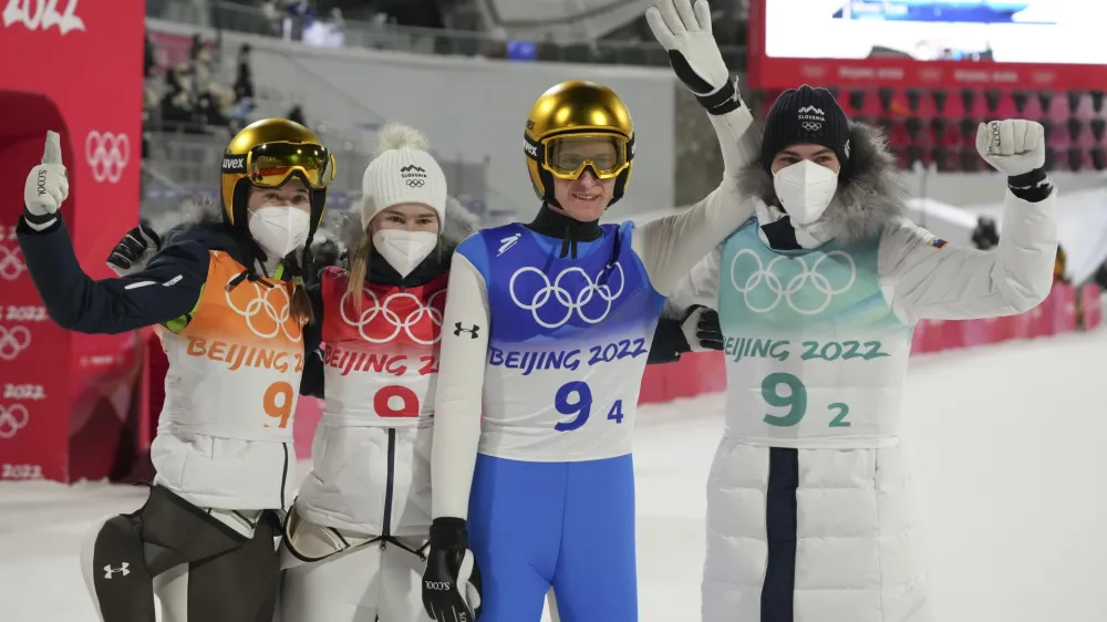 Slovenia's Ursa Bogataj, left, Nika Kriznar, second from left, Peter Prevc, second from right, and Timi Zajc celebrates after winning gold in the ski jumping mixed team event at the 2022 Winter Olympics, Monday, Feb. 7, 2022, in Zhangjiakou, China. (AP Photo/Matthias Schrader)