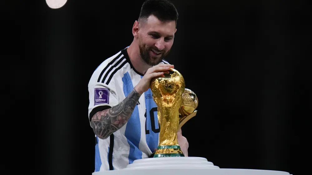 Argentina's Lionel Messi holds best player of the tournament trophy as he touches the World Cup trophy after the World Cup final soccer match between Argentina and France at the Lusail Stadium in Lusail, Qatar, Sunday, Dec. 18, 2022. (AP Photo/Petr David Josek)