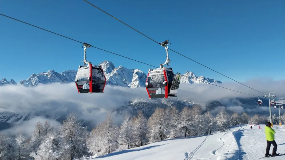 Zimsko kuliso ustvarijo mogočni in zasneženi vrhovi Dolomitov, ki se zdijo skoraj na dosegu rok. 