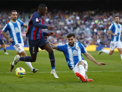 Barcelona's Ousmane Dembele, 2nd left is tackled by Espanyol's Leandro Cabrera during a Spanish La Liga soccer derby match between Barcelona and Espanyol at the Camp Nou stadium in Barcelona, Spain, Saturday, Dec. 31, 2022. (AP Photo/Joan Monfort)