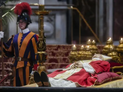 A Vatican Swiss Guard stands by the body of late Pope Emeritus Benedict XVI lying out in state inside St. Peter's Basilica at The Vatican where thousands went to pay their homage. Pope Benedict, the German theologian who will be remembered as the first pope in 600 years to resign, has died, the Vatican announced Saturday, Dec. 31, 2022. He was 95. (AP Photo/Gregorio Borgia)