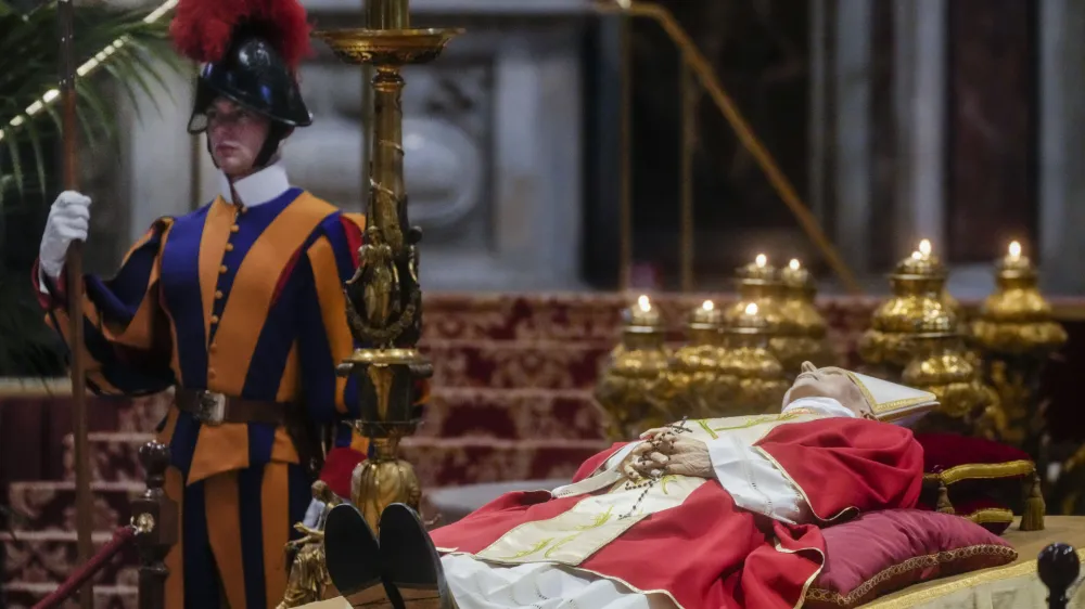 A Vatican Swiss Guard stands by the body of late Pope Emeritus Benedict XVI lying out in state inside St. Peter's Basilica at The Vatican where thousands went to pay their homage. Pope Benedict, the German theologian who will be remembered as the first pope in 600 years to resign, has died, the Vatican announced Saturday, Dec. 31, 2022. He was 95. (AP Photo/Gregorio Borgia)