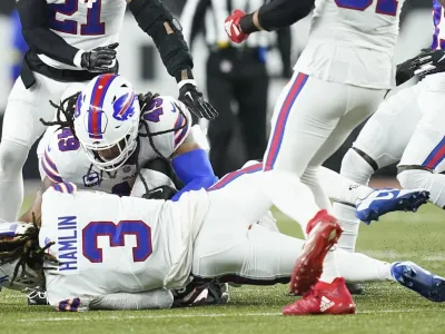 CLARIFIES THAT IMAGE SHOWN IS FROM THE END OF A TACKLE SECONDS BEFORE HAMLIN COLLAPSED - Buffalo Bills safety Damar Hamlin (3) lies on the turf after making a tackle on Cincinnati Bengals wide receiver Tee Higgins, who is blocked from view, as Buffalo Bills linebacker Tremaine Edmunds (49) assists at the end of the play during the first half of an NFL football game between the Cincinnati Bengals and the Buffalo Bills, Monday, Jan. 2, 2023, in Cincinnati. After getting up from the play, Hamlin collapsed and was administered CPR on the field. (AP Photo/Joshua A. Bickel)