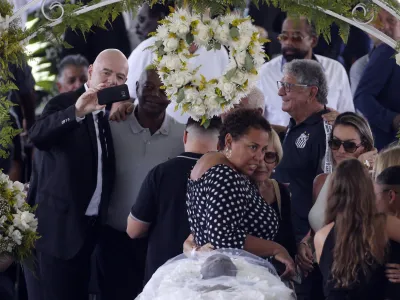 Soccer Football - Death of Brazilian soccer legend Pele - Vila Belmiro Stadium, Santos, Brazil - January 2, 2023 SENSITIVE MATERIAL. THIS IMAGE MAY OFFEND OR DISTURB FIFA president Gianni Infantino takes a selfie, and Pele's daughter, Kelly Cristina Nascimento is pictured with mourners as the body of Brazilian soccer legend Pele is seen in his casket, as he lays in state on the pitch of his former club Santos' Vila Belmiro stadium REUTERS/Diego Vara