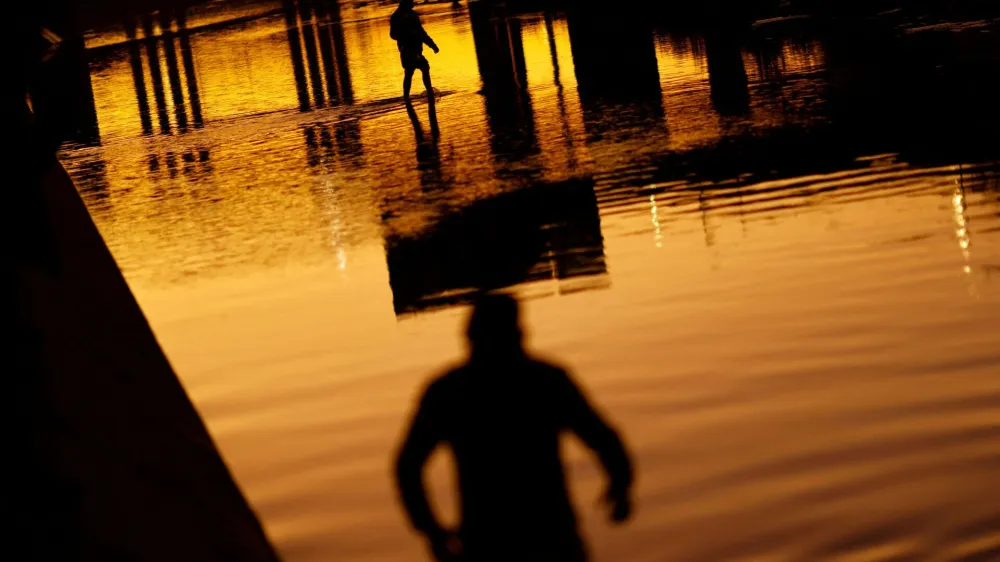 Asylum-seeking migrants cross the Rio Bravo river, the border between the United States and Mexico, to request asylum in El Paso, Texas, U.S., as seen from Ciudad Juarez, Mexico December 21, 2022. REUTERS/Jose Luis Gonzalez   TPX IMAGES OF THE DAY