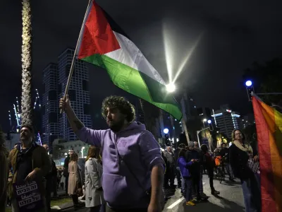 A protester holds a Palestinian flag in Tel Aviv, Israel, at a demonstration against Prime Minister Benjamin Netanyahu's far-right government, Saturday, Jan. 7, 2023. Thousands of Israelis protested plans by Netanyahu's government that opponents say threaten democracy and freedoms. (AP Photo/ Tsafrir Abayov)