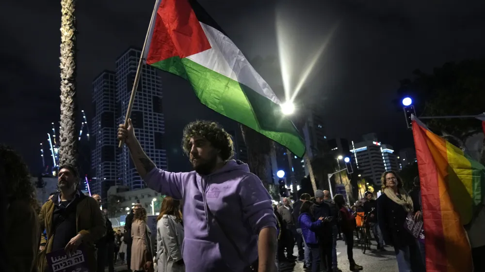 A protester holds a Palestinian flag in Tel Aviv, Israel, at a demonstration against Prime Minister Benjamin Netanyahu's far-right government, Saturday, Jan. 7, 2023. Thousands of Israelis protested plans by Netanyahu's government that opponents say threaten democracy and freedoms. (AP Photo/ Tsafrir Abayov)