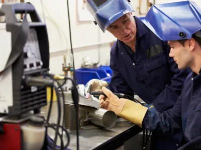 Engineer Teaching Apprentice To Use TIG Welding Machine At Work