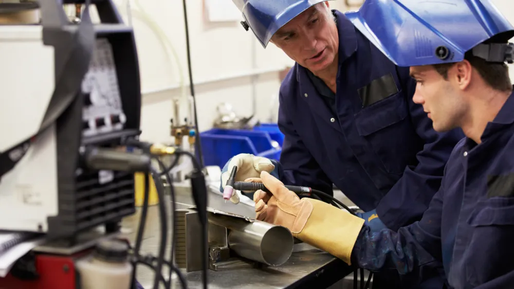 Engineer Teaching Apprentice To Use TIG Welding Machine At Work