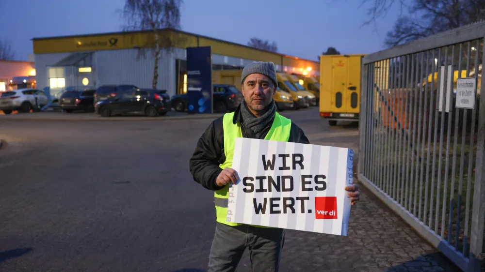 20 January 2023, Berlin: The shop steward Ahmet Almaz from the parcel delivery Reinickendorf holds a placard during a nationwide postal strike. In the collective bargaining dispute at Deutsche Post, the Verdi union had called for nationwide strikes. Photo: Joerg Carstensen/dpa