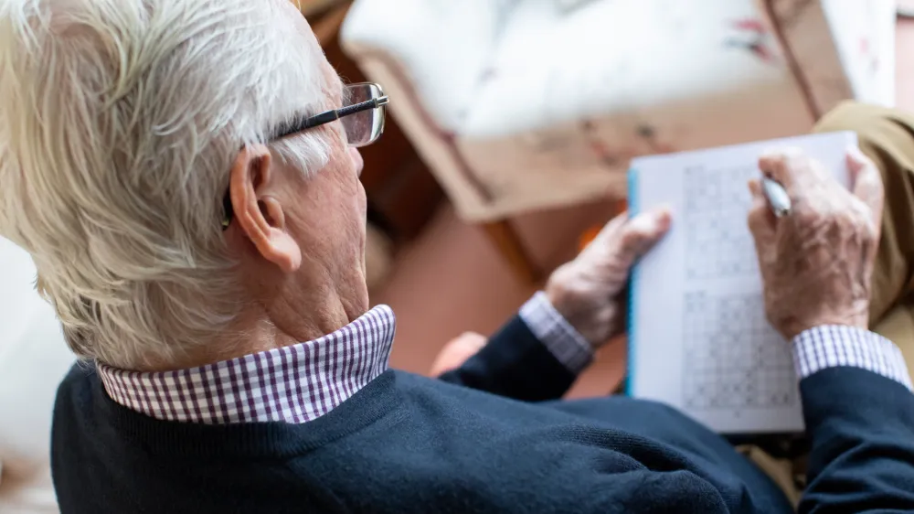 Senior Man Doing Sudoku Puzzle At Home