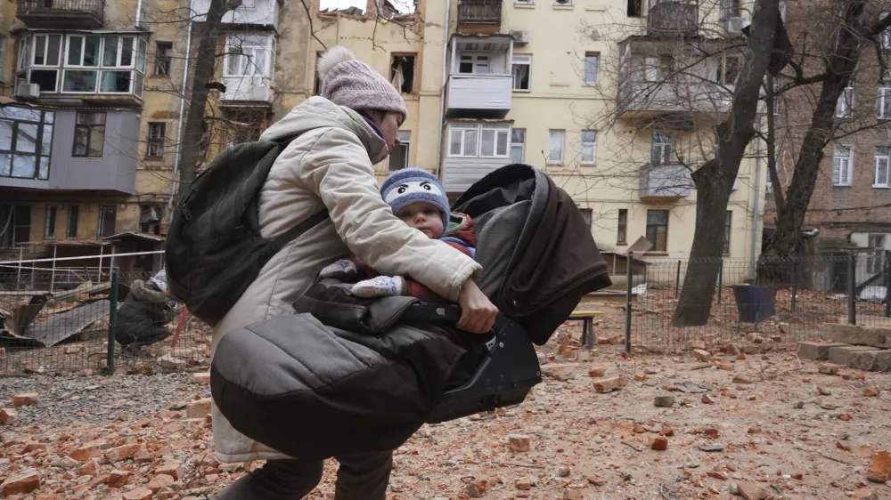 A woman carries her child as they evacuate from a residential building which was hit by a Russian rocket at the city center of Kharkiv, Ukraine, Monday, Jan. 30, 2023. Russian shelling killed at least five people and wounded 13 others during the previous 24 hours, Ukrainian authorities said Monday as the Kremlin's and Kyiv's forces remained locked in combat in eastern Ukraine. (AP Photo/Andrii Marienko)