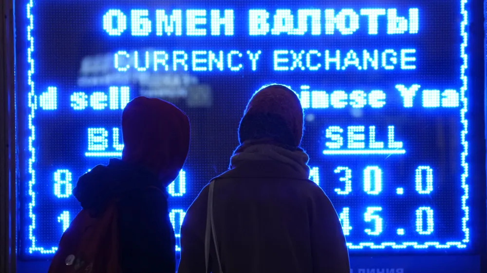Women look at a screen displaying exchange rate at a currency exchange office in St. Petersburg, Russia, Tuesday, March 1, 2022. The Russian currency plunged about 30% against the U.S. dollar Monday after Western nations announced moves to block some Russian banks from the SWIFT international payment system and to restrict Russia's use of its massive foreign currency reserves. (AP Photo/Dmitri Lovetsky)
