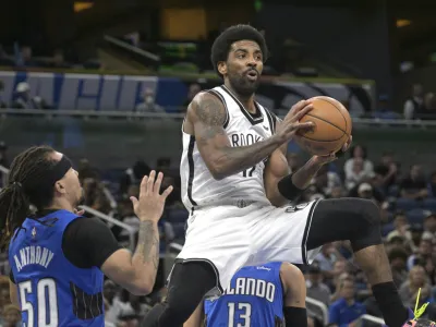 Brooklyn Nets guard Kyrie Irving (11) looks to pass after driving to the basket as Orlando Magic guard Cole Anthony (50) defends during the first half of an NBA basketball game Tuesday, March 15, 2022, in Orlando, Fla. (AP Photo/Phelan M. Ebenhack)