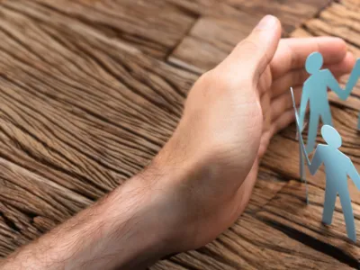 Cropped image of businessman's hands covering paper team on wooden table