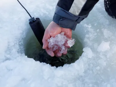 Indigenous fisherman Mike Diabo scoops shush out of a freshly drilled ice fishing hole on a lake in the Kitigan Zibi Anishinabeg Reserve, Quebec, Canada, February 22, 2023. First Nations ice fishermen risk going out on ice as climate change affects the quality of the ice. REUTERS/Blair Gable