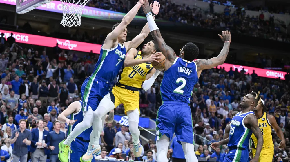 Feb 28, 2023; Dallas, Texas, USA; Indiana Pacers guard Tyrese Haliburton (0) is fouled by Dallas Mavericks center Dwight Powell (7) as guard Kyrie Irving (2) defends the basket during the second half at the American Airlines Center. Mandatory Credit: Jerome Miron-USA TODAY Sports