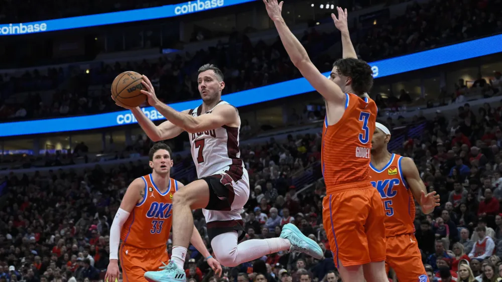 Chicago Bulls guard Goran Dragic (7) passes the ball away from between Oklahoma City Thunder center Mike Muscala (33), forward Darius Bazley, back, and guard Josh Giddey (3) during the second half of an NBA basketball game Friday, Jan. 13, 2023, in Chicago. (AP Photo/Matt Marton)