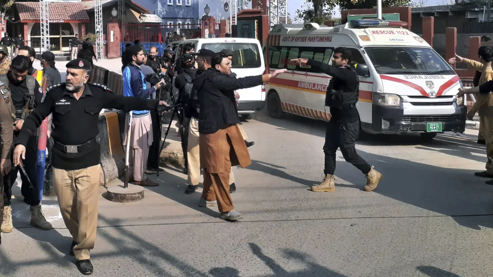 Police officers clear the way for ambulances leaving after carrying wounding people from bomb explosion site, at the main entry gate of police offices, in Peshawar, Pakistan, Monday, Jan. 30, 2023. A powerful bomb went off Monday near a mosque and police offices in the northwestern Pakistani city of Peshawar, killing at least a few people and wounding some 70 worshippers, police and government officials said. (AP Photo/Muhammad Sajjad)