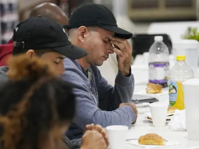 Roberto Sotolongo prays after dinner at the Iglesia Rescate, Tuesday, Feb. 21, 2023, in Hialeah, Fla. Sotolongo, from Havana, Cuba, crossed the U.S. Mexican border into the U.S. in November, leaving behind his wife and children. Sotolongo, a carpenter by trade, finds himself in limbo without a work permit to sustain himself and help his family in Cuba. (AP Photo/Marta Lavandier)