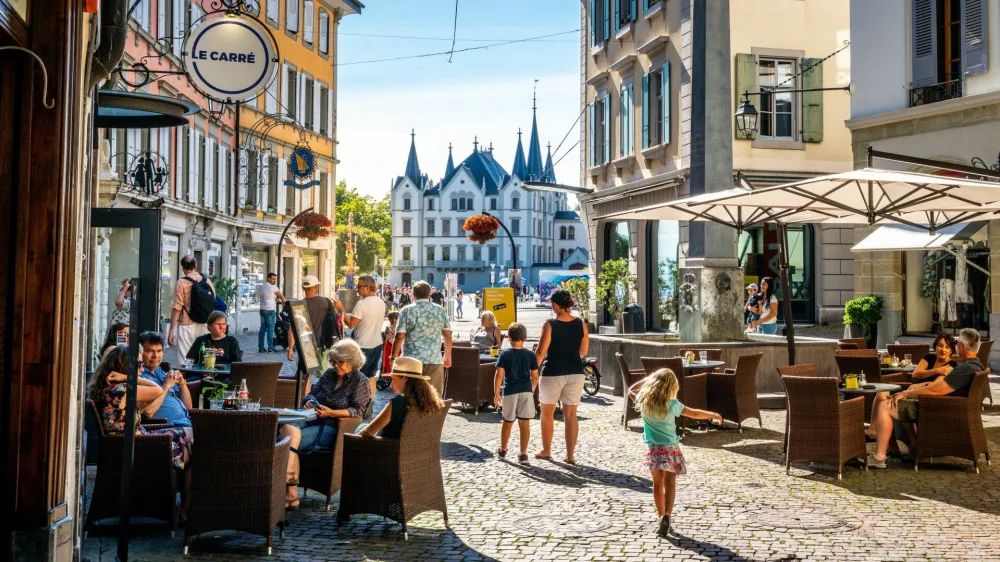 Vevey Switzerland, 4 July 2020: Scenic view of Vevey old town with people at cafe terrace and Aile castle in background on sunny summer day in Vevey Vaud Switzerland