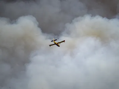 Smoke raises from a forest fire burning below as a firefighting plane flies over San Agustin, Spain on Friday March 24, 2023 Hundreds of people were evacuated as a major forest fire raged in Spain's eastern Castellon region on Friday, marking the early start to the nation's fire season amid bone dry conditions. (Lorena Sopena/Europa Press via AP)