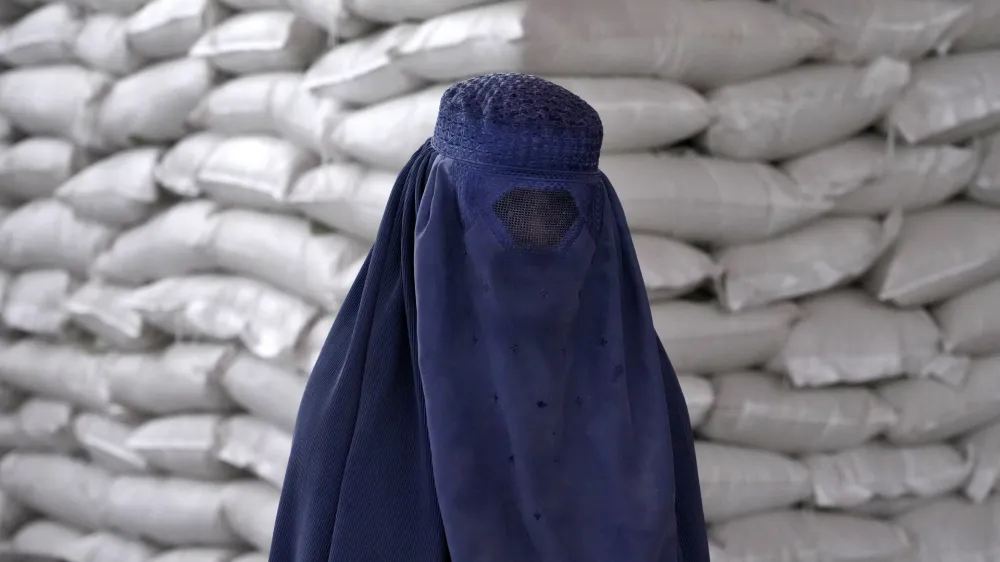 FILE - An Afghan woman waits to receive a food ration distributed by a South Korean humanitarian aid group, in Kabul, Afghanistan, May 10, 2022. (AP Photo/Ebrahim Noroozi, File)