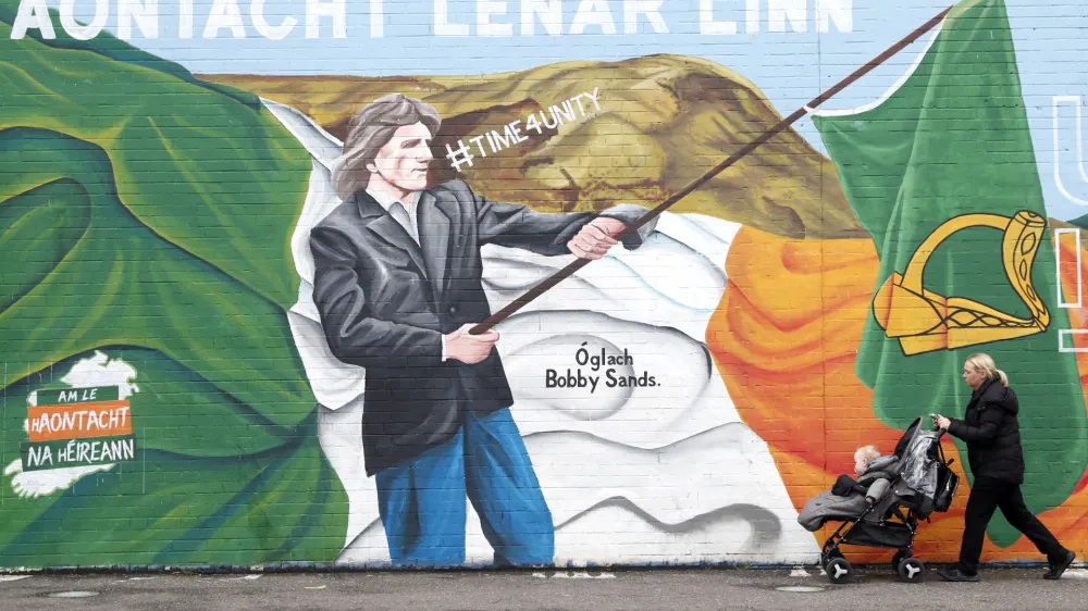 A woman walks past an Irish republican mural in West Belfast, Northern Ireland, Tuesday, March 28, 2023. British intelligence (MI5) raised the Northern Ireland terrorism threat level Tuesday from substantial to severe meaning an attack is highly likely by dissident Irish Republican's. (AP Photo/Peter Morrison)