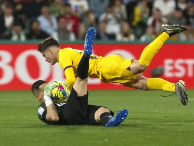 Elche's goalkeeper Edgar Badia, left, makes a save in front of Barcelona's Gavi during a Spanish La Liga soccer match between Elche and Barcelona, at the Martinez Valero Stadium in Elche, Spain, Saturday, April 1, 2023. (AP Photo/Alberto Saiz)