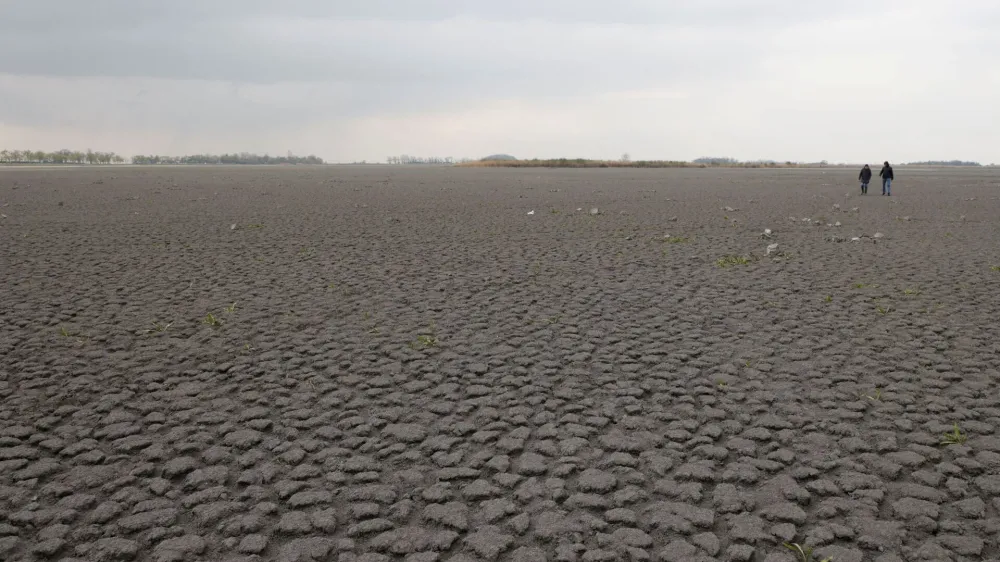 People walk on dried up Lake Zicksee near Sankt Andrae, Austria, April 9, 2023. REUTERS/Leonhard Foeger