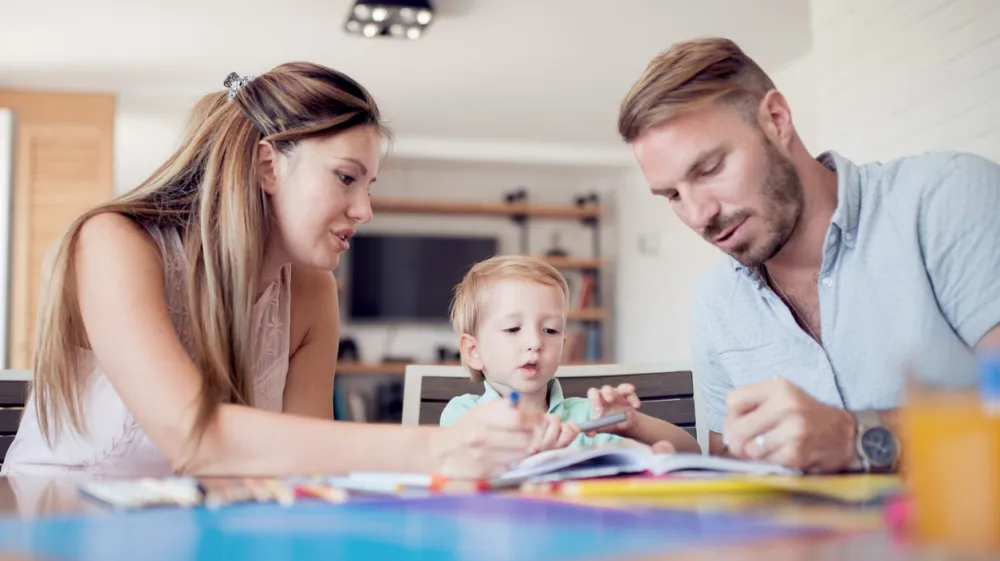 Smiling family drawing together in living room at home.