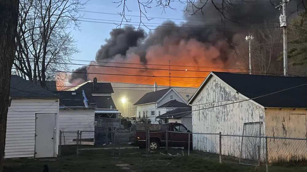 This photo provided by Julie Roe shows smoke rising from a former factory site in Richmond, Ind., Tuesday, April 11, 2023. An evacuation order affecting more than 1,000 people was expected to remain in place through Wednesday, April 12, around the large industrial fire in Richmond, near the Ohio border, where crews worked through the night to douse piles of burning plastics, authorities said. (Julie Roe via AP)