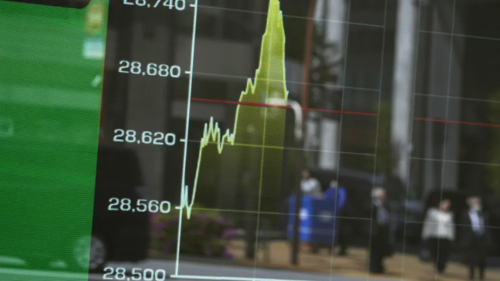 An electronic stock board shows the morning movement of Japan's Nikkei 225 index with passersby seen reflected on it, Friday, April 21, 2023 in Tokyo. Shares are weaker in Asia after benchmarks dipped on Wall Street following mixed earnings reports from big companies and more signals the U.S. economy may be slowing. (AP Photo/Shuji Kajiyama)